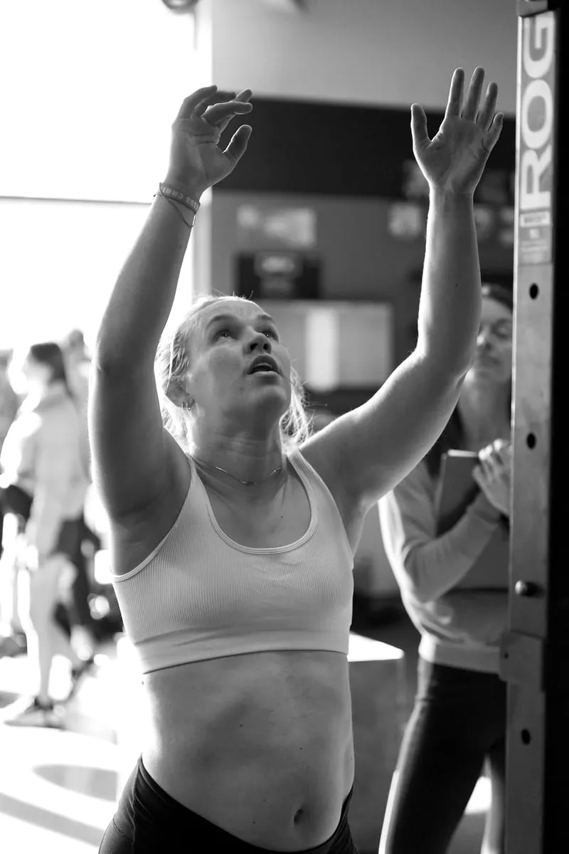 An XD FIT member raising her arms after finishing a workout as a coach counts reps